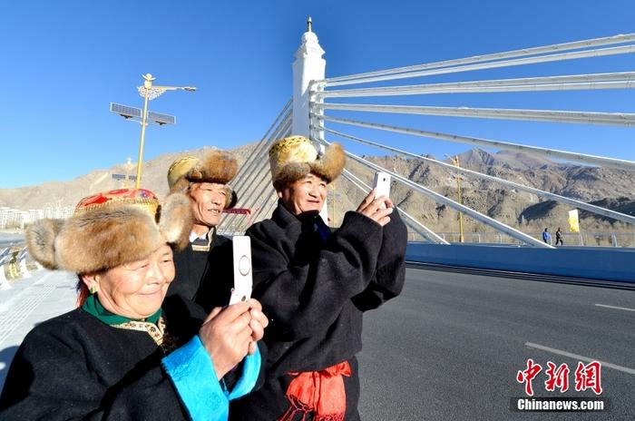 资料图为2013年11月27日，拉萨市纳金村村民用手机拍摄正式通车的纳金大桥。 <a target='_blank' href='/'>中新社</a>记者 李林 摄 　
