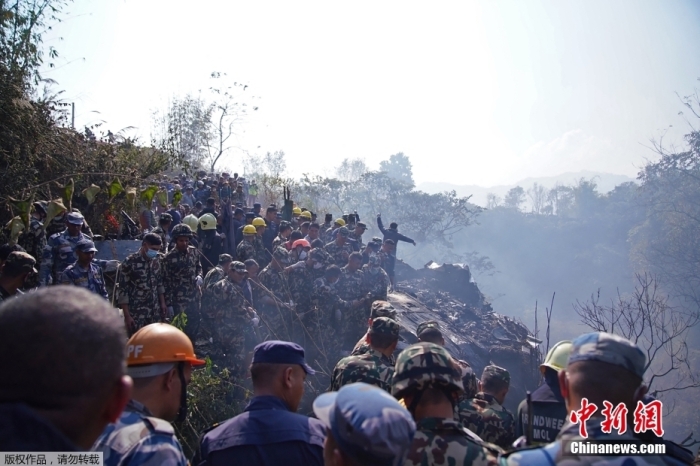图为救援人员和人群聚集在飞机残骸周围。
