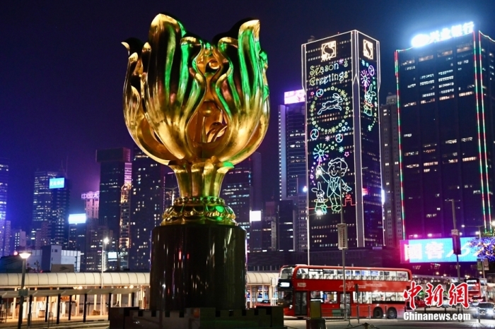 1月19日，香港金紫荆广场的“永远盛开的紫荆花”铜雕与周边大厦的贺年灯饰交相辉映。农历新年即将到来，香港街头的新春气氛越来越浓。　 <a target='_blank' href='/'>中新社</a>记者 李志华 摄