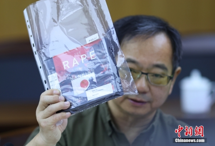 鲁照宁展示由美国音像公司发行的一套七张光盘的张纯如著作《南京浩劫：二战中被遗忘的大屠杀》。a