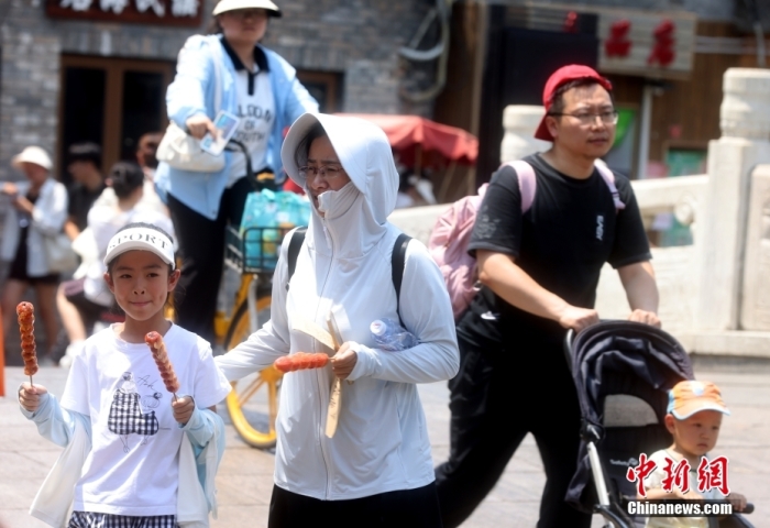 6月23日，北京什刹海，游人在烈日下出行。当日，北京市气象台升级发布高温红色预警信号。中新社记者 张宇 摄