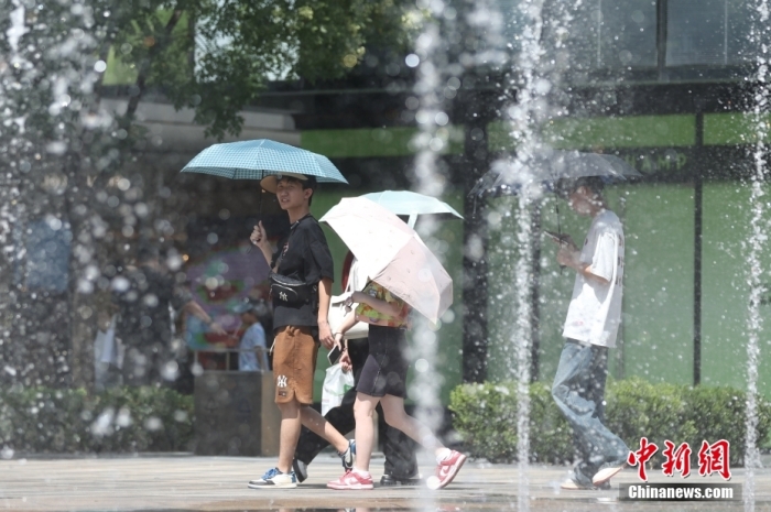 7月6日，代表“北京温度”的南郊观象台气温继5日之后再次突破40℃，北京7月气温连续两天超40℃。图为北京市民撑伞出行。中新社记者 蒋启明 摄