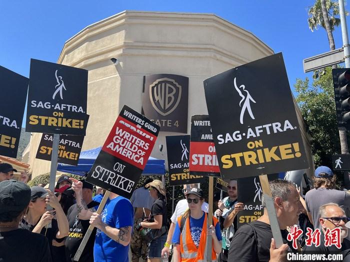 当地时间7月14日上午，华纳兄弟、迪士尼等美国影视娱乐产业巨头总部门前，有成百上千的人高举“罢工”标语牌游行示威。由于未能与美国电影和电视制片人联盟(AMPTP)就新合同达成协议，拥有约16万名会员的好莱坞三大工会之一美国影视演员协会(SAG-AFTRA)发起罢工，于14日起在洛杉矶和纽约的十余家制片公司外示威游行。  中新社记者 张朔 摄