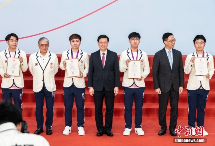 图为李家超(中)为中国香港电子竞技队颁发表扬状后与运动员合影。
中新社
记者 侯宇 摄