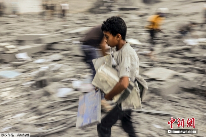 当地时间10月15日，沙地带南部拉法地区的废墟中，一名儿童在断壁残垣中搜寻可用的物品。