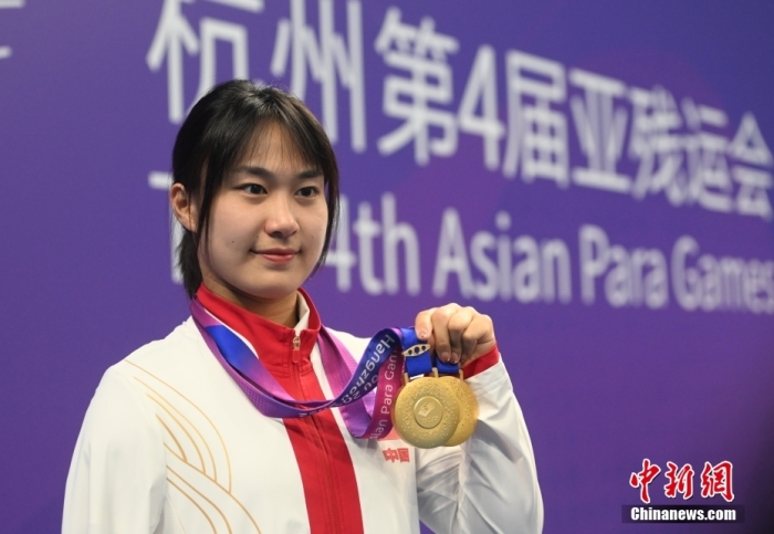 10月27日，杭州亚残运会游泳项目的比赛全部结束，中国队共获得56金52银42铜，队员们在赛后进行庆祝。图为蒋裕燕展示金牌。
中新社
记者 王刚 摄