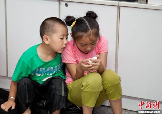 资料图为两名小学生在玩手机游戏。龙敏 摄