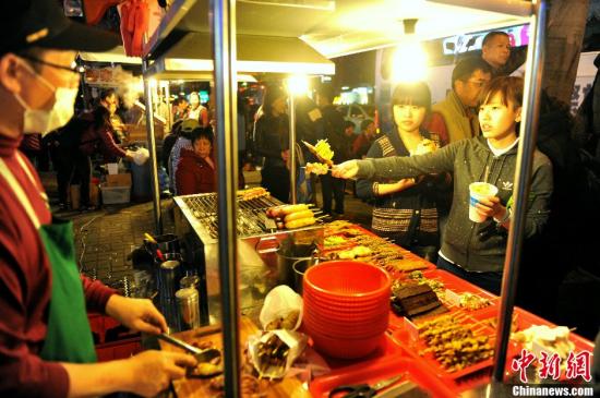 资料图：通过自由行来到台湾的两位大陆江苏女孩正在台北士林夜市品尝美食。中新社发 王东明 摄