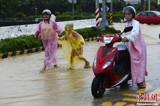 8月29日，台湾嘉义县，民众在被雨淹没的马路出行。受台风“康妮”影响，嘉义降下大暴雨，多条马路被淹。台风“康妮”给台湾中南部地区带来超大豪雨，截至上午11时37分，台湾水利部门对9个县市发布一级淹水警戒。超大豪雨区域包括屏东县、高雄市、台南市、嘉义县、云林县、南投县、台中市、嘉义市；大豪雨区域包括台北市、新北市、桃园县、新竹县、苗栗县、彰化县。刘震 摄