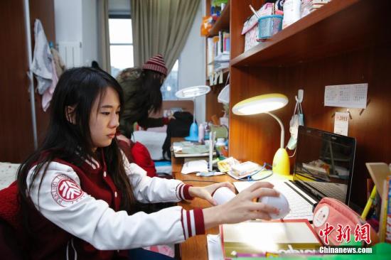 12月17日，在北京大学留学生宿舍内，泰国华裔留学生白云莹(前)与李慧敏正在收拾房间。在她们的书桌上摆满了各类汉语书籍。中新社发 王骏 摄
