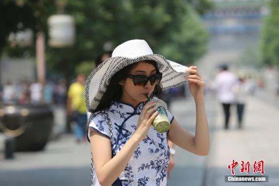 5月25日，北京高温，行人在北京前门大街行走。 中新社发 熊然 摄