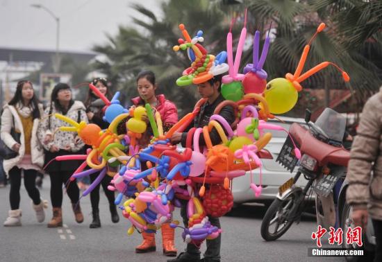 重庆洋人街景区人气爆棚。图为一商贩身上挂满彩色气球。 中新社记者 陈超 摄