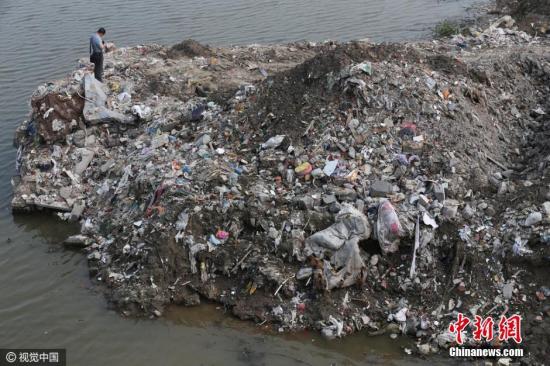 2016年7月17日，江苏省海门市的江心沙农场新江海河一座桥附近偷倒的垃圾。据运载垃圾货船上的船员透露，这些垃圾也是从上海运来。图片来源：视觉中国