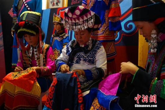 资料图：非物质文化传承人正在对彝族服装进行刺绣。邹立杨 摄