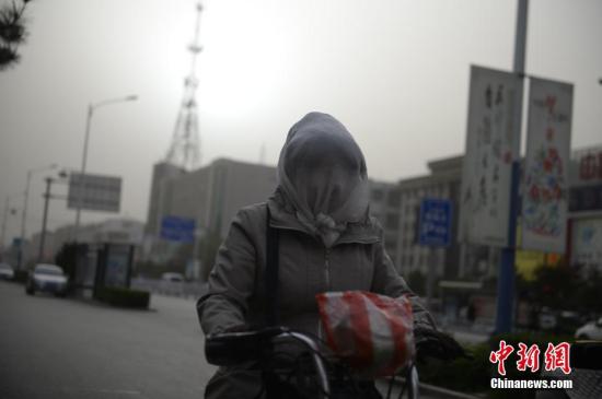 资料图 民众头裹纱巾应对沙尘天。 中新社记者 刘文华 摄