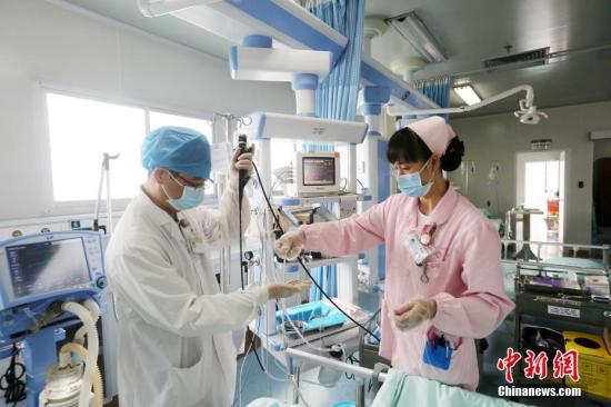 资料图：在广西柳州市融安县人民医院重症医学科，一名护士配合医生为一名重症患者做治疗。谭凯兴 摄