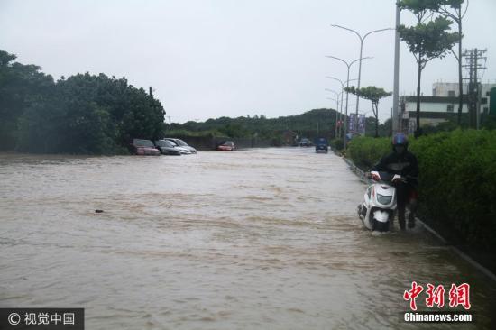 资料图：台湾暴雨来袭，骑摩托车者推车前行。图片来源：视觉中国