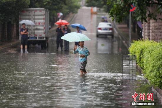 市民在积水的道路中出行。中新社记者 贺俊怡 摄