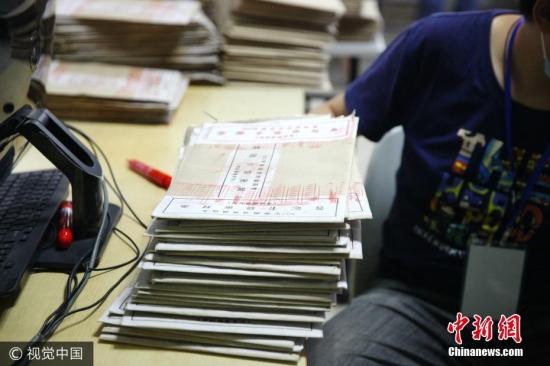 6月12日，海口，在海南师范大学高考评卷场，工作人员将试卷封条拆开并进行扫描入电脑。石磊 摄 图片来源：视觉中国