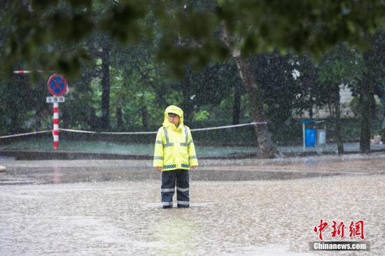 资料图：6月13日，浙江省金华市浦江县大雨倾盆，交警冒雨执勤，阻拦车辆进入漫水路段。 中新社发 张浩钺 摄