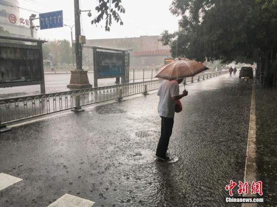 图为北京阜成门，一位市民撑伞出行。 中新网记者 富宇 摄