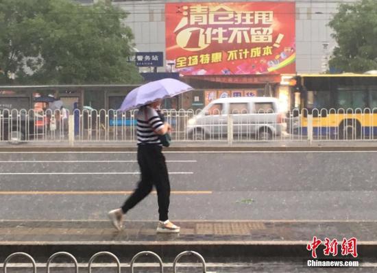 6月23日清晨，北京降雨持续，并出现了短时大雨。据北京市气象局官方微博消息，北京市气象台今日6时发布：今天白天小到中雨并伴有雷电，傍晚局地伴有短时大风或冰雹，北转东风2、3级，最高气温24℃；夜间有雷阵雨，东转北风2、3级，最低气温19℃。图为北京阜成门，一位市民撑伞出行。 中新网记者 富宇 摄