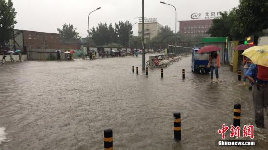 6月23日清晨，北京降雨持续，并出现了短时大雨。图为朝阳区双合家园出现积水，民众趟水出行。 中新网记者 赵姗姗 摄