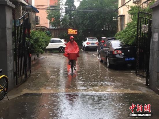 北京百万庄附近，市民雨中骑行。 中新网记者 富宇 摄
