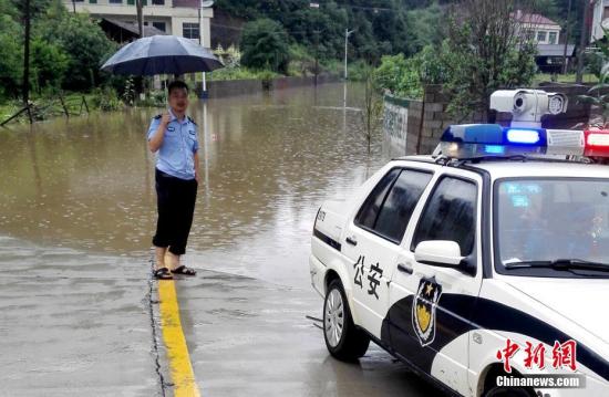 入汛以来，湖南多地先后降下暴雨。6月22日开始，湖南桃江县遭遇今年最强降雨，加之上游水库泄洪，资江桃江段水位连日来持续上涨，造成多地被洪水浸没。6月24日，桃江县警民联动，在洪水肆掠的地段，积极引导人流、车流，一道转移人员、物资，力争将洪灾损失降到最低。图为民警在危险路段值守。 王鹏 摄