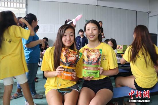 两名美国华裔青少年手捧袋装螺蛳粉合影。 林馨 摄