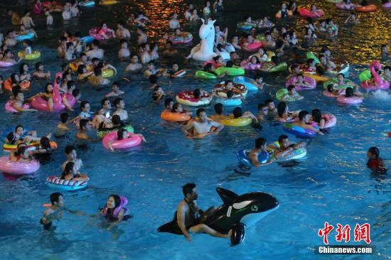 7月8日晚，民众在冲浪池中戏水。当日，为躲避持续高温闷热的天气，大批民众在夜色中涌进南京欢乐水魔方水上乐园戏水，在清凉中度周末。 中新社记者 泱波 摄