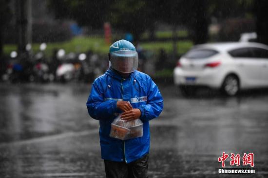 资料图：外卖小哥冒雨送餐。中新社记者 刘冉阳 摄
