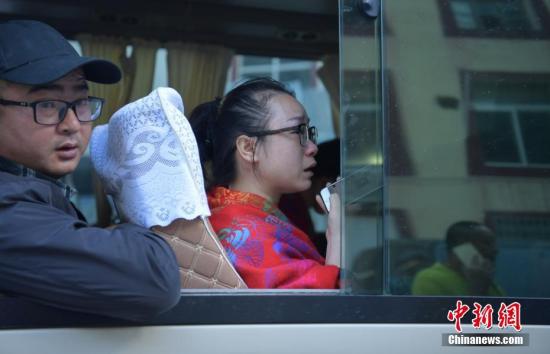 来自湖南的游客周女士(前)上车后边哭边用手机给家人报平安。 中新社记者 刘忠俊 摄