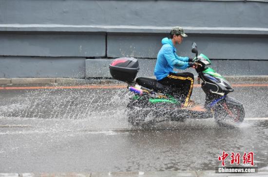 资料图：8月17日，辽宁沈阳，市民在雨中出行。当日，辽宁省气象灾害监测预警中心12时59分发布暴雨橙色预警信号。中新社记者 于海洋 摄