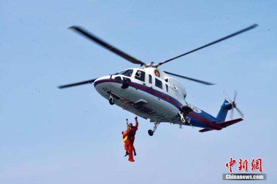 16名中国航天员和2名欧洲航天员，8月21日在山东省烟台市附近海域圆满完成了为期17天的海上救生训练任务。图为训练期间，8月17日，直升机悬吊营救训练。 中新社发 朱九通 摄