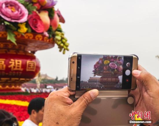 9月25日，民众在北京天安门广场国庆主题花篮前拍照。中新社记者 贾天勇 摄