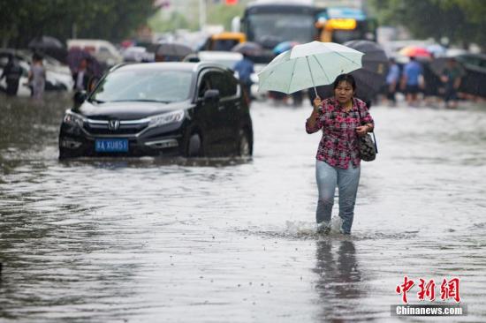 资料图：9月25日，南京城东银城东苑门口的道路上，市民在积水中涉水而行。泱波 摄
