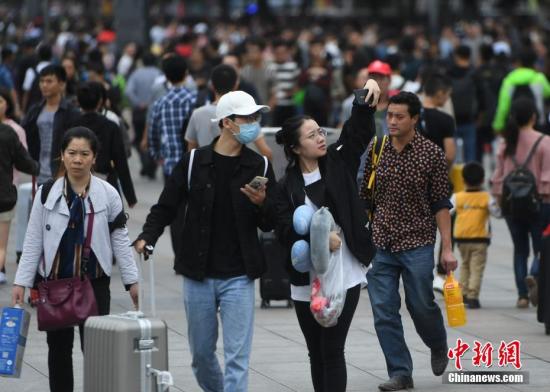 9月30日，全国多地迎来国庆假期客流高峰。图为重庆旅客在火车站广场上玩自拍。 中新社记者 陈超 摄