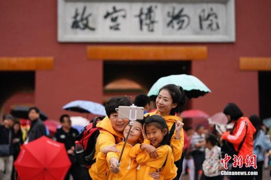 10月2日，北京小雨，游客在故宫博物院游览。根据国家旅游局数据中心综合测算，中国国庆假期首日，全国当天共接待游客1.13亿人次，同比增长10.5%，实现旅游收入965亿元，同比增长12.2%。中新社记者 杜洋 摄