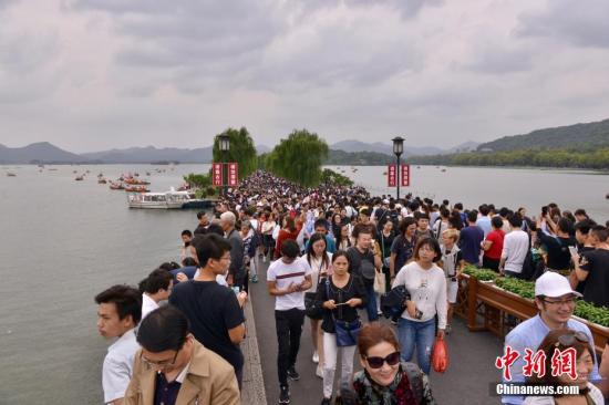 10月3日，国庆长假第三天，来自全国各地的游客在杭州断桥欣赏西湖美景。 中新社记者 李晨韵 摄