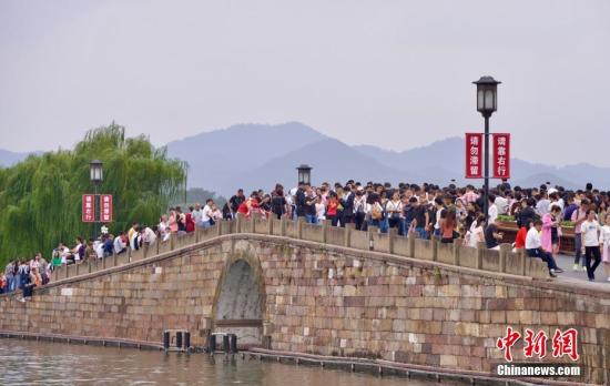 10月3日，国庆长假第三天，大量游客涌入西湖断桥。 中新社记者 李晨韵 摄