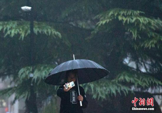 资料图：市民在雨中自拍。 中新社记者 刘关关 摄