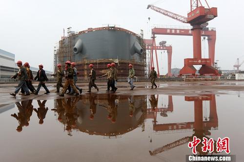 图为江苏泰州一家造船厂内，工人从正在建造的船前经过。(资料图片)中新社记者 泱波 摄