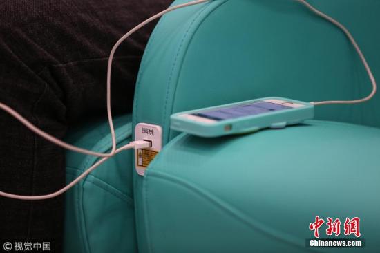 资料图：大连火车北站候车室座椅给手机充电。图片来源：视觉中国