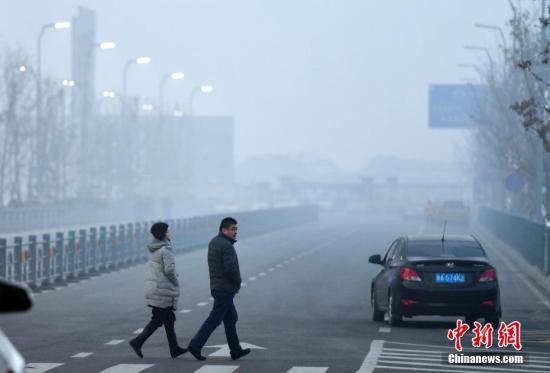 12月20日傍晚时分，华灯初上的新疆乌鲁木齐市依旧被雾霾天气所笼罩，外出民众脚步匆匆。据环保部网站全国城市空气质量小时报数据显示：当日18时，乌鲁木齐市AQI指数为266，首要污染物为PM2.5，空气质量级别为重度污染。 中新社记者 刘新 摄