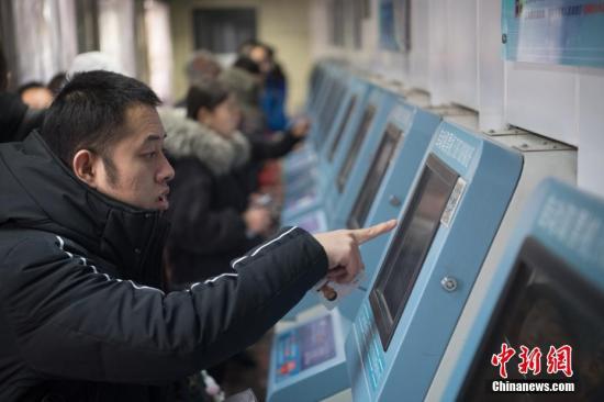 1月4日，山西太原火车站，使用网络购票的旅客在自动取票机上领取火车票。中新社记者 韦亮 摄