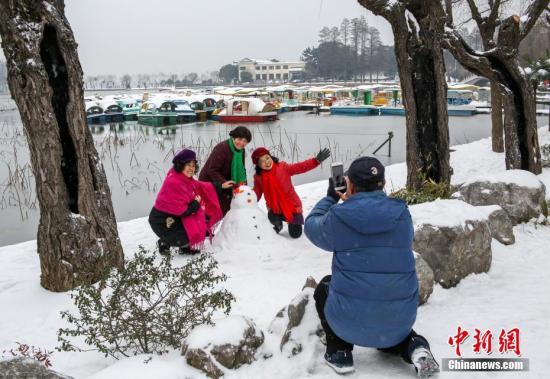 资料图：武汉市民在雪中拍照。中新社记者 张畅 摄