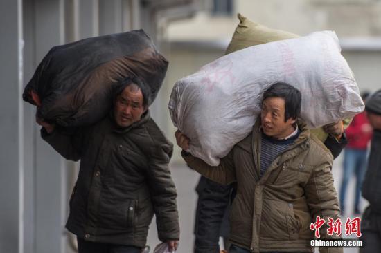 资料图：春运期间农民工扛着大小行李返乡。中新社记者 韦亮 摄