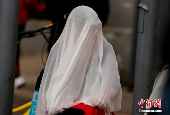 3月28日，雾霾沙尘齐聚京城，除此前启动的空气重污染橙色预警之外，官方还发布了今年首个沙尘蓝色预警。在两者“夹攻”之下，全城空气质量已达到严重污染水平。图为北京街头一市民用纱巾包裹自己。 中新社记者 杜洋 摄