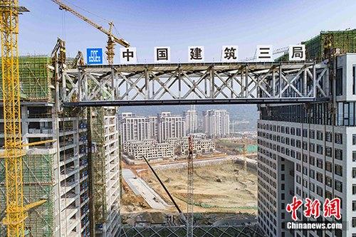 3月28日早6时，在武汉中建・光谷之星项目施工现场，高9.9米、宽18米、跨度76.5米的钢结构连廊成功提升至73.6米高空并横卧于两座塔楼之间。该工程创下中国内地建筑史上一项新记录：成为中国内地高层建筑钢结构连廊整体提升跨度最大的一个。中新社记者 李经纬 摄